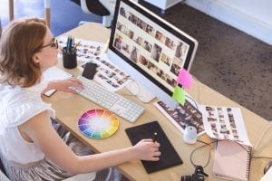 Female graphic designer working on graphic tablet and computer at desk