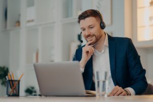 Professional male operator works in callcenter uses headset and laptop computer talks on video call